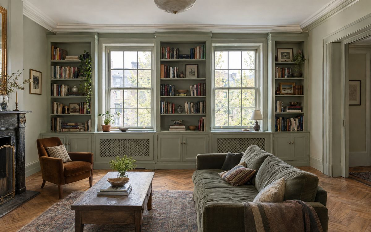 Painted built-in cabinets and bookcases with radiator covers under the windows in a prewar living room, design concept