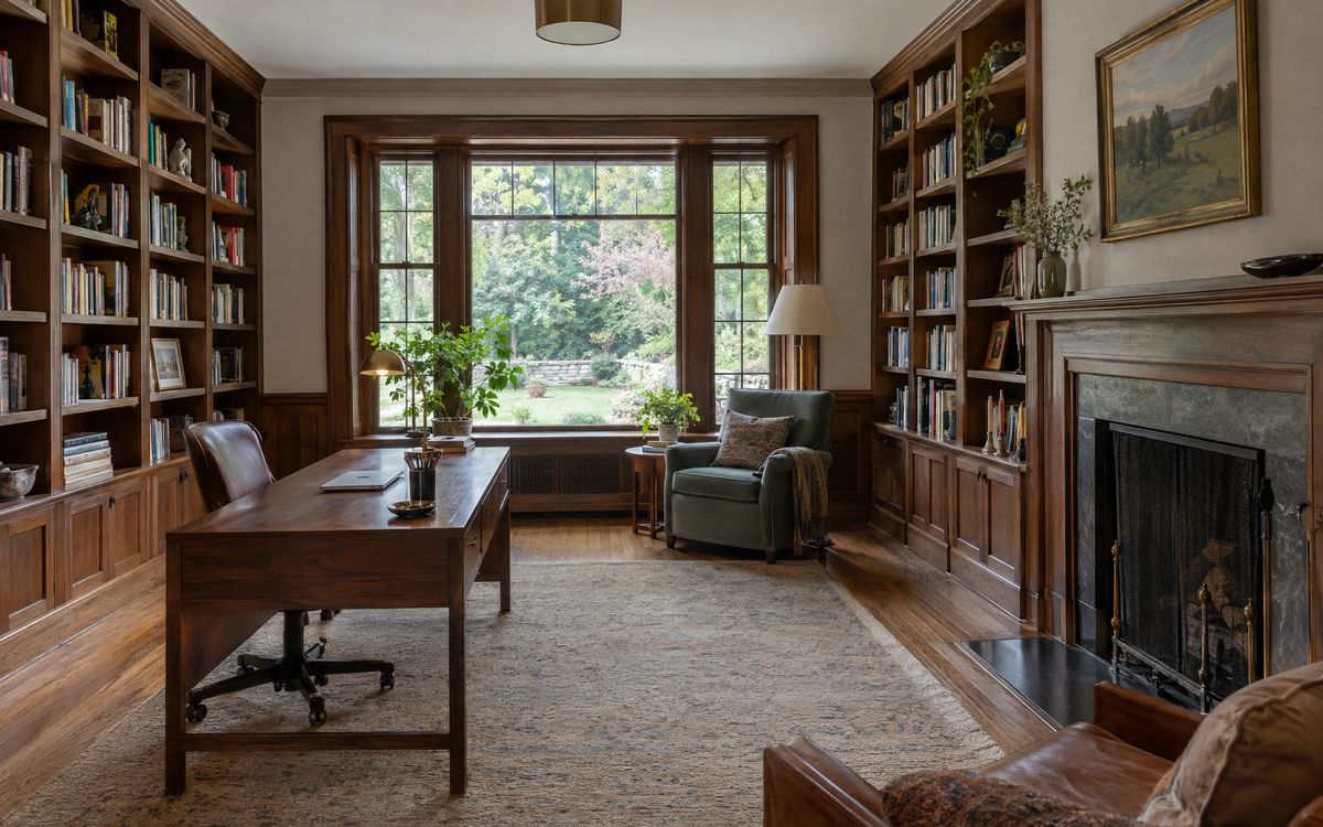 A walnut home library with a desk and fireplace in a Fieldston, Bronx house, design concept